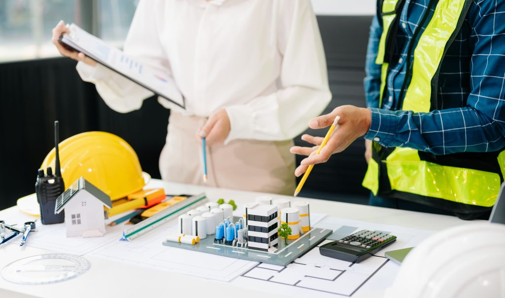 Construction professionals discussing architectural plans and building models at a meeting